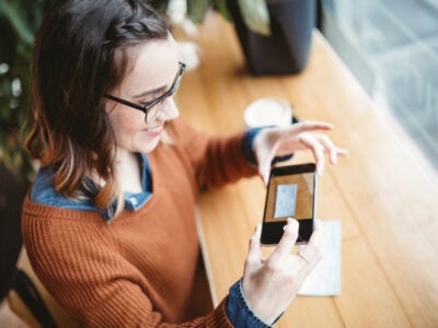 young woman takes a mobile deposit photo of a paycheck