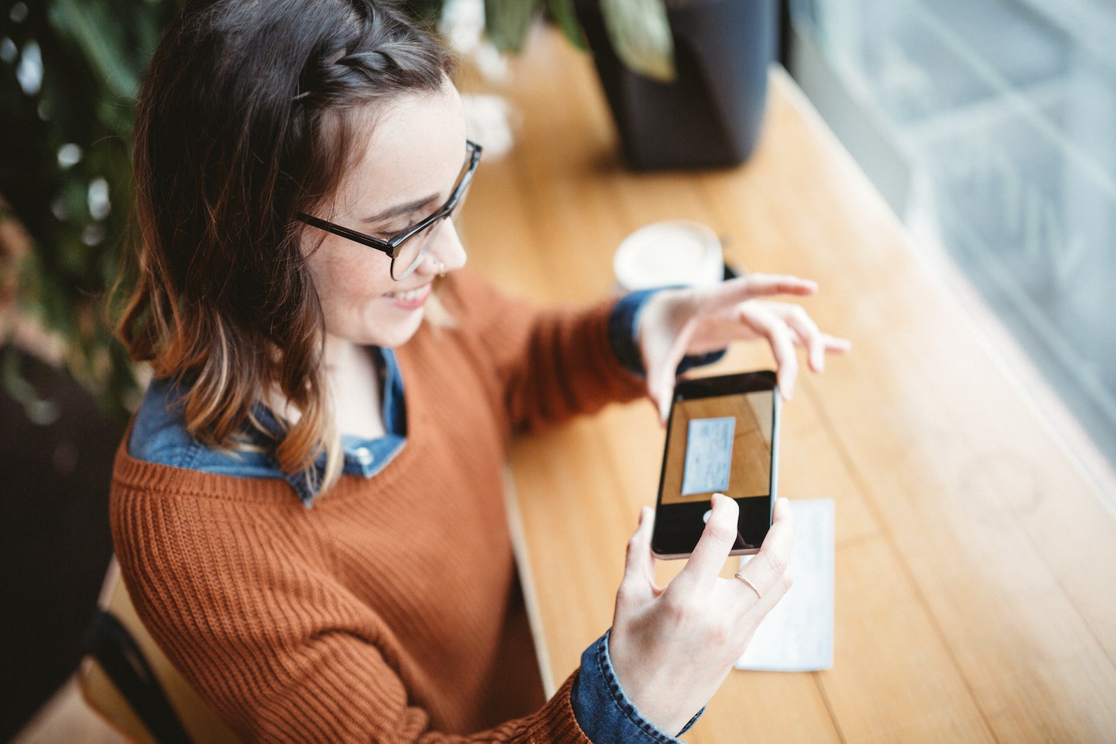 young woman takes a mobile deposit photo of a paycheck