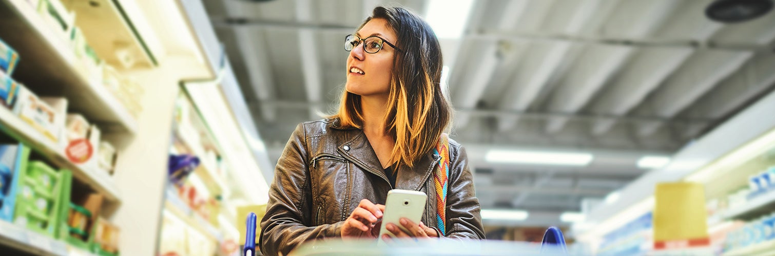 gen z girl shopping in grocery store with smartphone