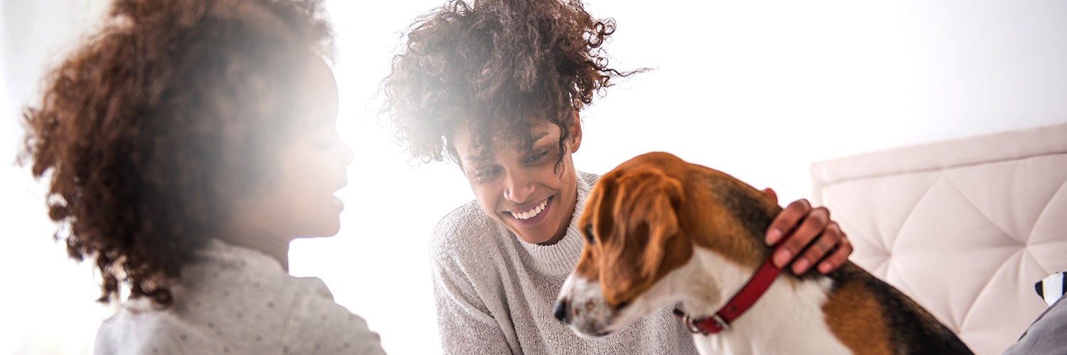 Young mother spending time with daughter playing with dog.