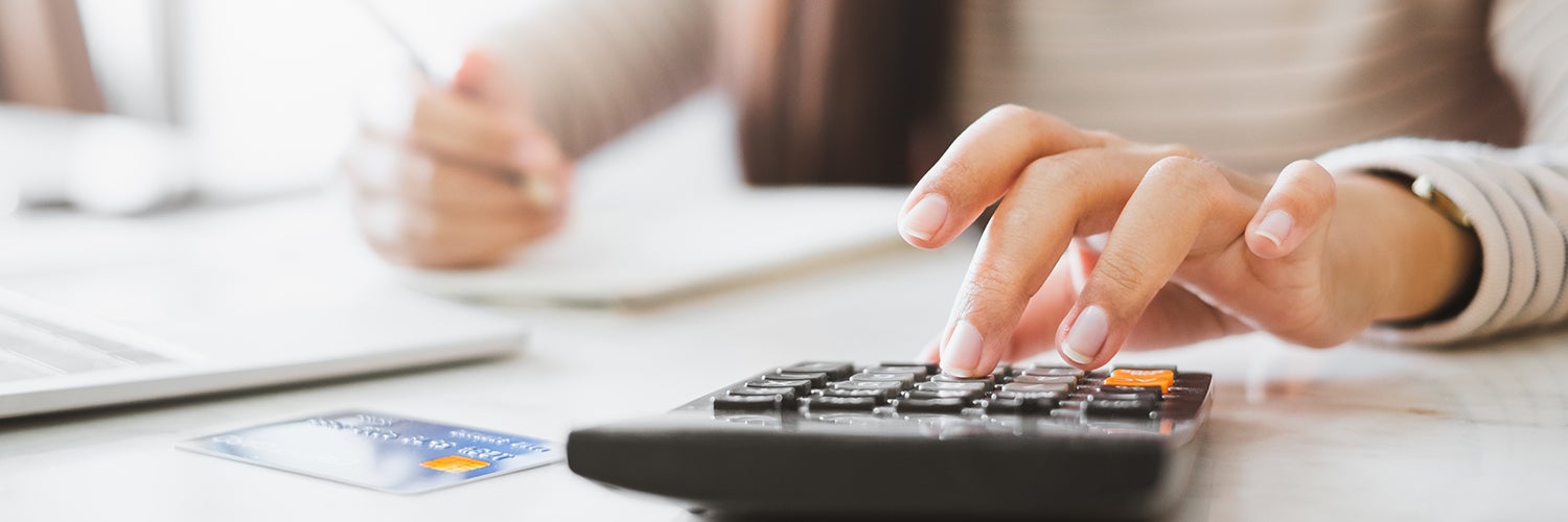 Una mujer presupuesta sus finanzas en una calculadora.