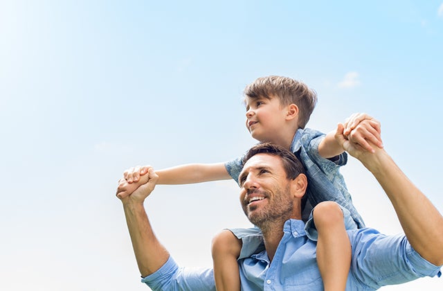 A father holding his son on his shoulders.