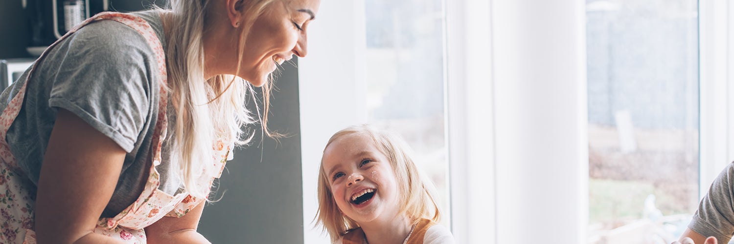 A woman and her daughter work in the kitchen together.