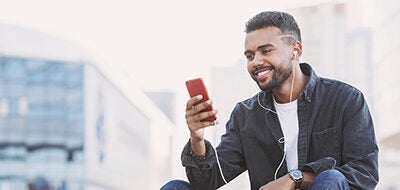 Man looking at his phone while wearing earphones