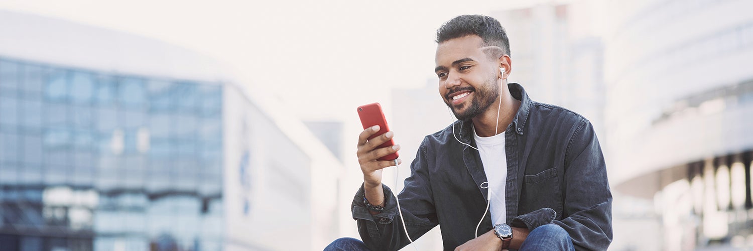 Un hombre mira su teléfono mientras usa auriculares.