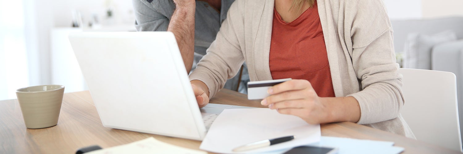 A couple looks at a computer while holding a credit card.