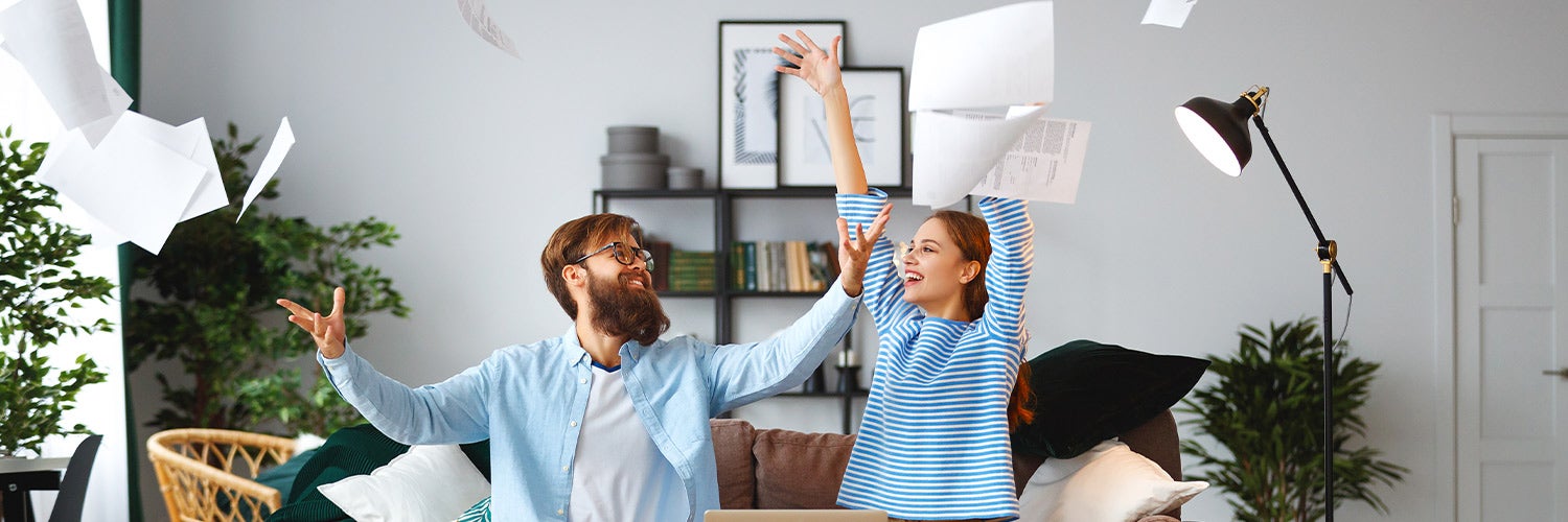 A couple happily throws papers into the air.