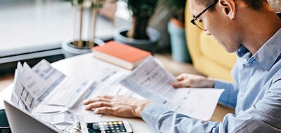 A man reviews financial papers on a desk in front of him.