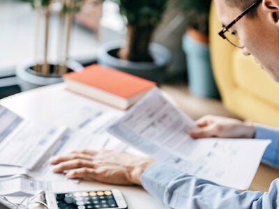 A man reviews financial papers on a desk in front of him.