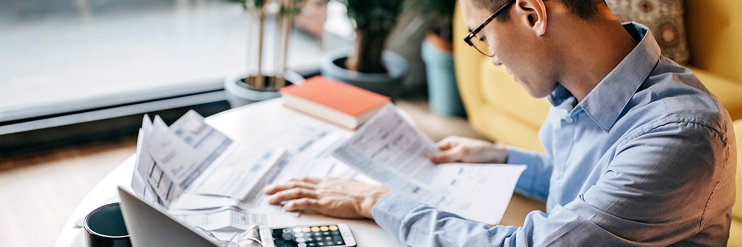 A man reviews financial papers on a desk in front of him.