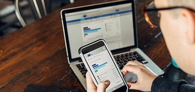 Man looking at cell phone and laptop