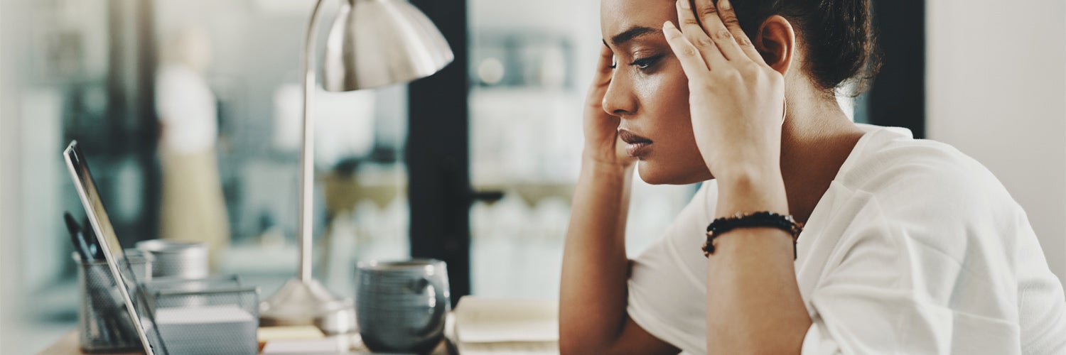 Stressed woman with hands on her head looking at a laptop.