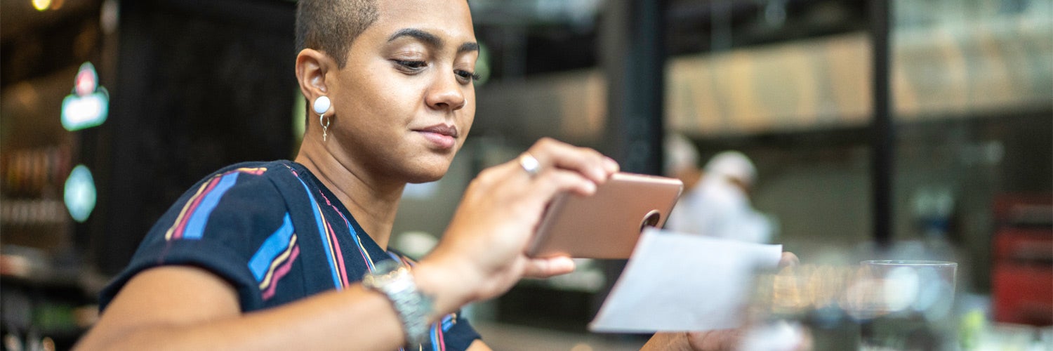 Woman holding phone depositing check.