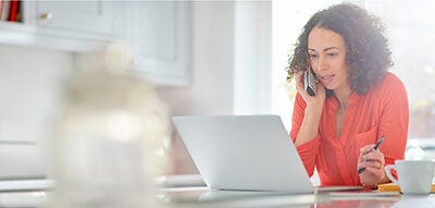 Woman on the phone looking at a laptop.
