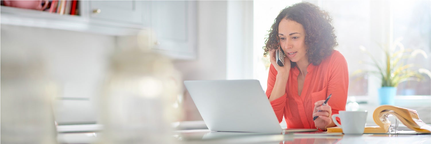 Woman on the phone looking at a laptop.