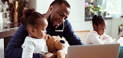 Man and daughter sit in front of a laptop.