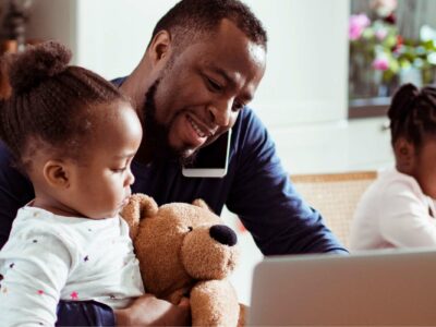 Man and daughter sit in front of a laptop.