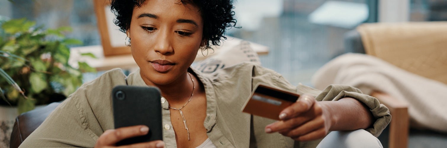 Woman holding phone and credit card.