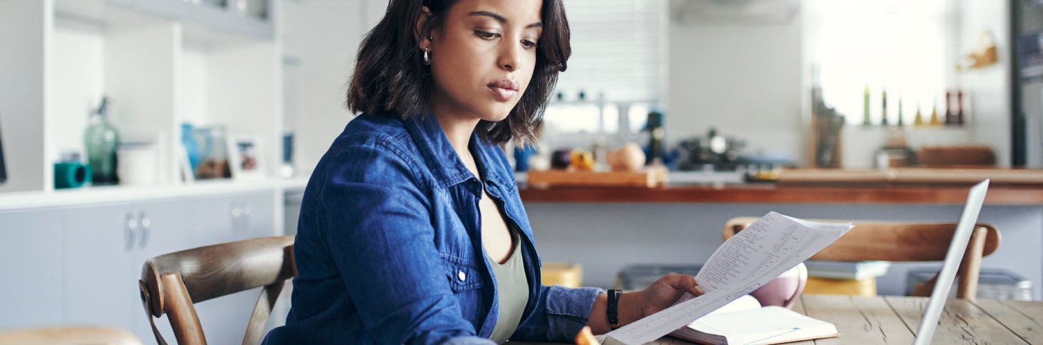 Woman looking at papers while on her computer.