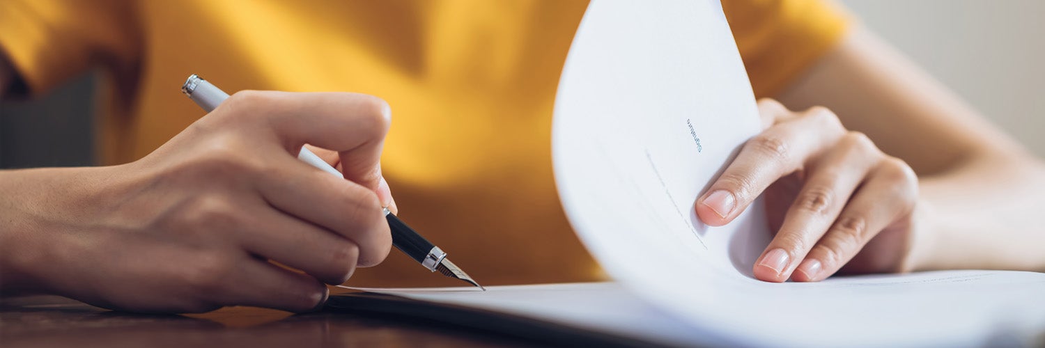 Person filing out documents with a pen.